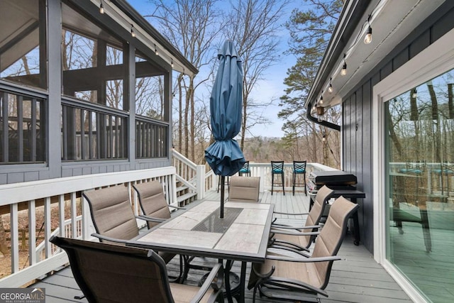 deck featuring a sunroom and outdoor dining space