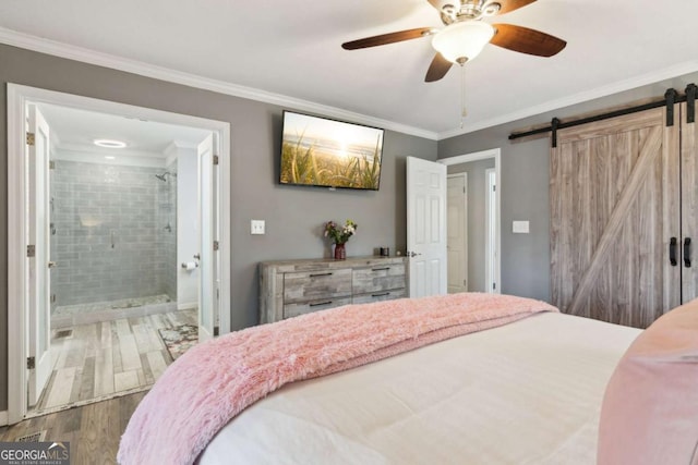 bedroom with ceiling fan, ensuite bathroom, a barn door, wood finished floors, and crown molding