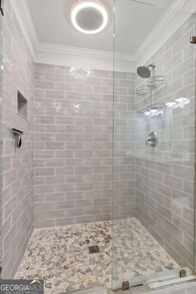 full bath with ornamental molding and tiled shower