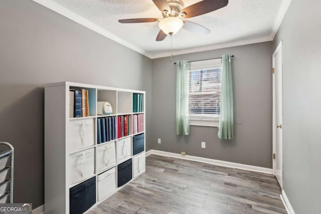 interior space featuring a textured ceiling, baseboards, wood finished floors, and crown molding