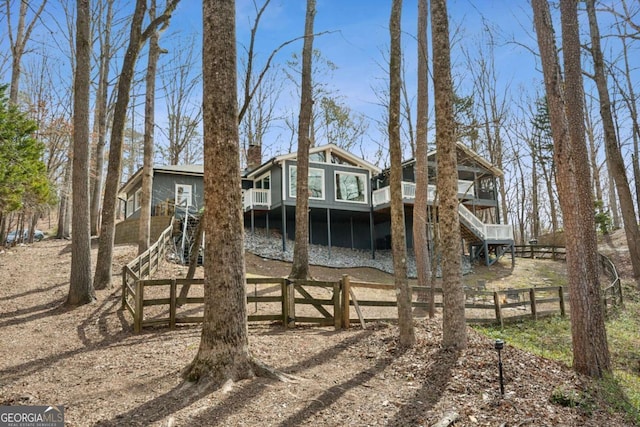 back of house with a sunroom, a chimney, stairs, fence, and a wooden deck