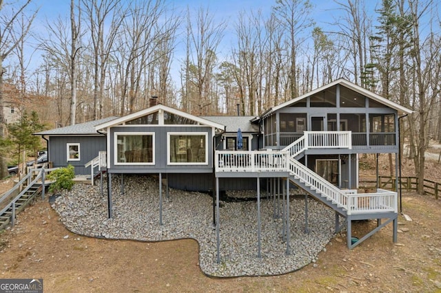 back of property featuring a sunroom, stairs, roof with shingles, a wooden deck, and a chimney