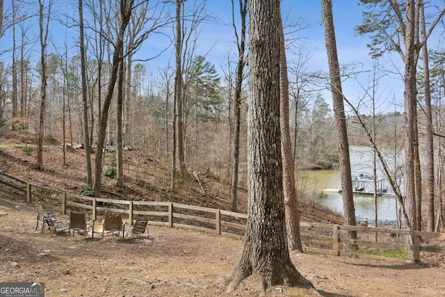 view of yard featuring a water view, fence, and a view of trees