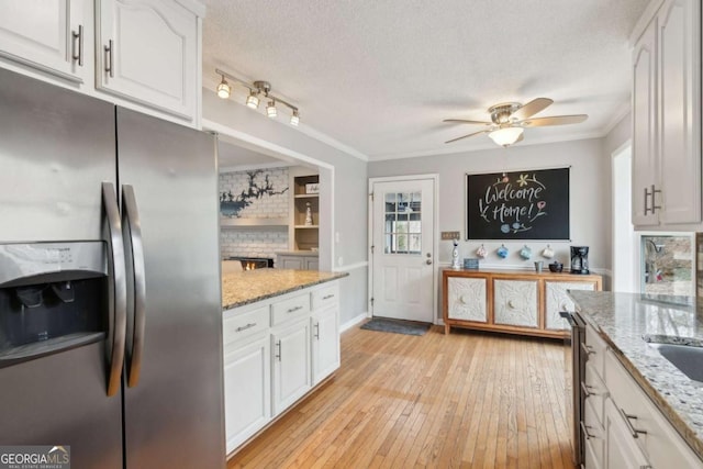 kitchen featuring light wood-style flooring, stainless steel fridge, a textured ceiling, and white cabinetry