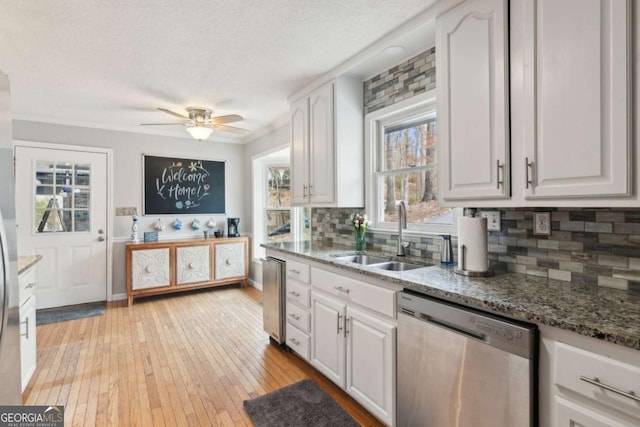 kitchen featuring light stone counters, a sink, white cabinets, light wood-type flooring, and dishwasher