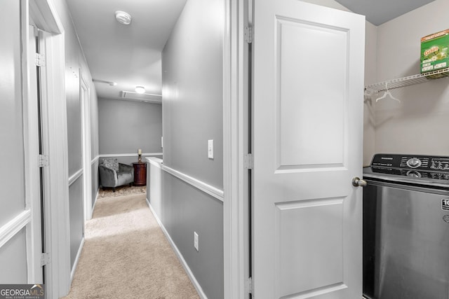 hall featuring light colored carpet, washer / clothes dryer, and baseboards