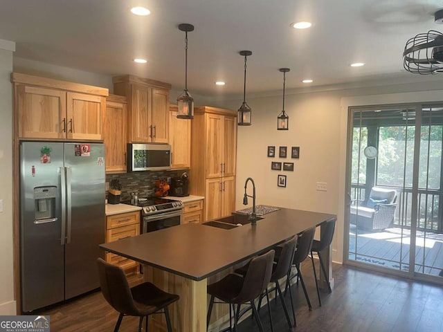 kitchen featuring dark wood-style floors, a kitchen breakfast bar, a sink, stainless steel appliances, and backsplash