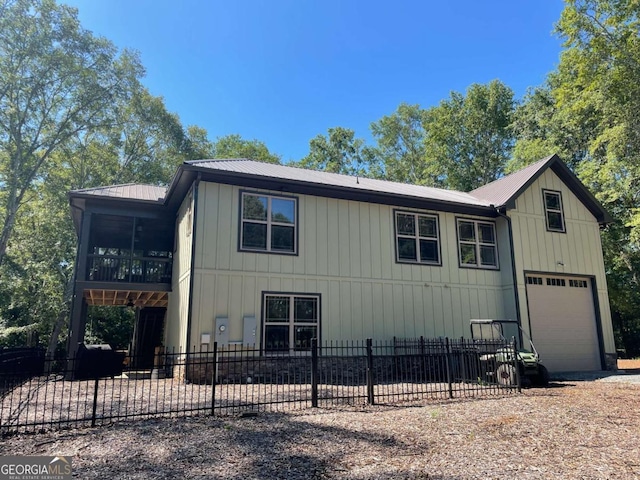 view of front of home with a fenced front yard, a sunroom, metal roof, and a garage