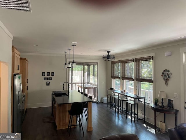 interior space featuring a kitchen island with sink, visible vents, baseboards, stainless steel refrigerator with ice dispenser, and dark wood finished floors