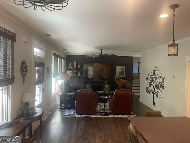 living room with visible vents, a ceiling fan, wood finished floors, stairs, and crown molding