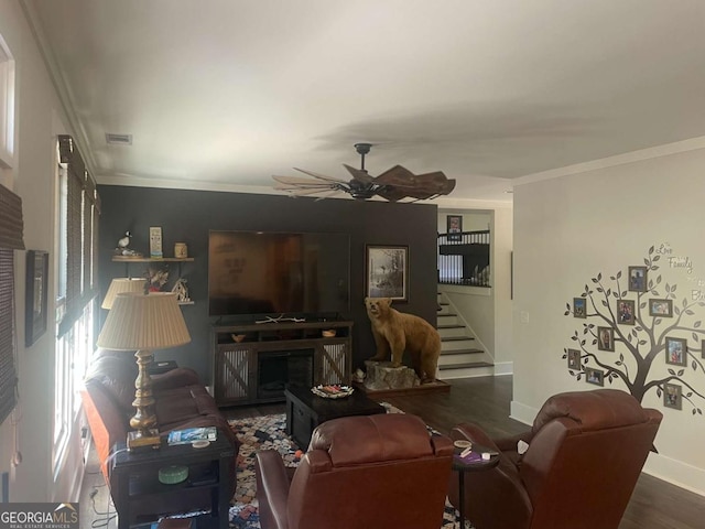 living room with wood finished floors, a ceiling fan, baseboards, stairs, and crown molding