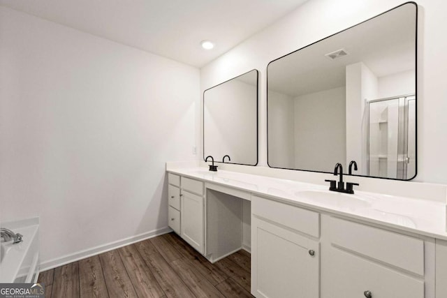 full bath with visible vents, double vanity, a stall shower, wood finished floors, and a sink