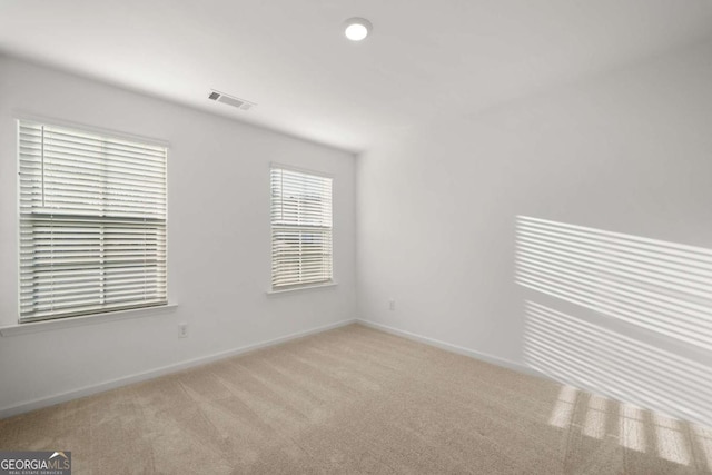 carpeted empty room with visible vents and baseboards