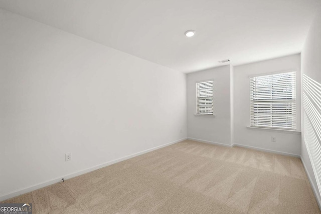 spare room with visible vents, baseboards, and light colored carpet