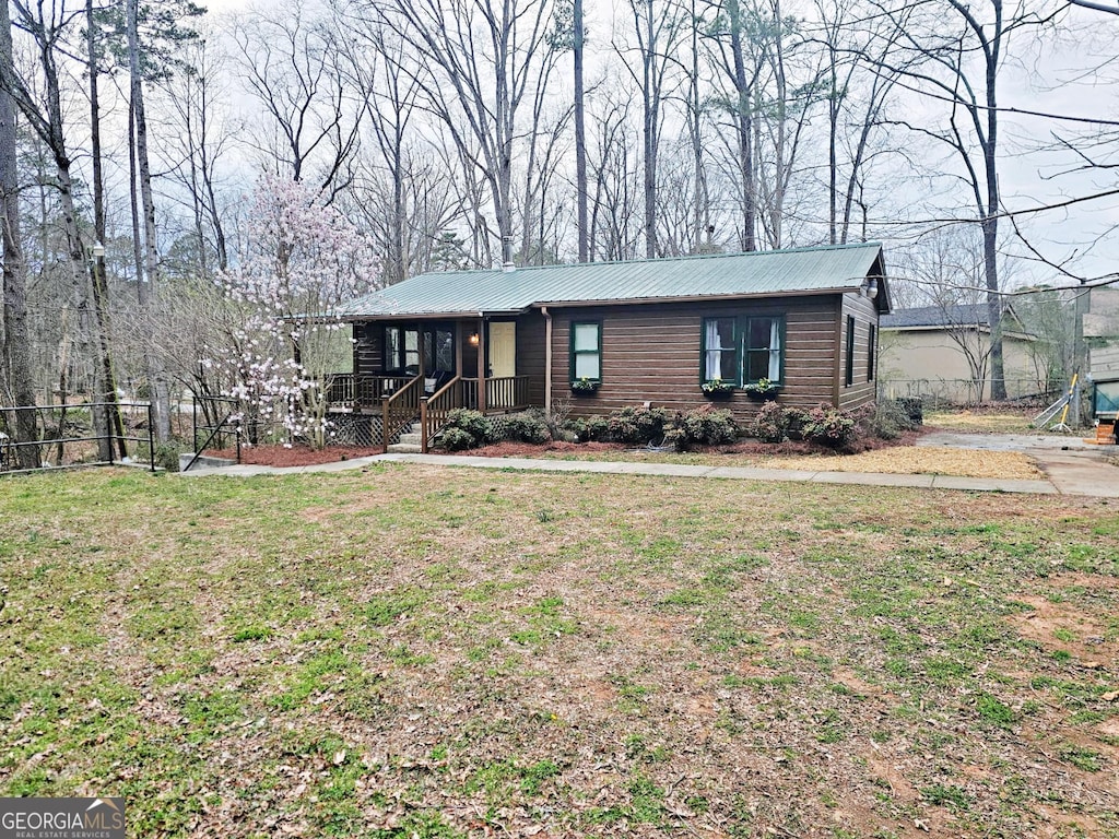 view of front facade with metal roof, a front yard, and fence