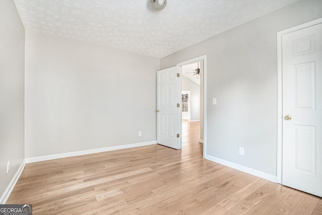 unfurnished bedroom featuring light wood-style flooring, baseboards, and a textured ceiling