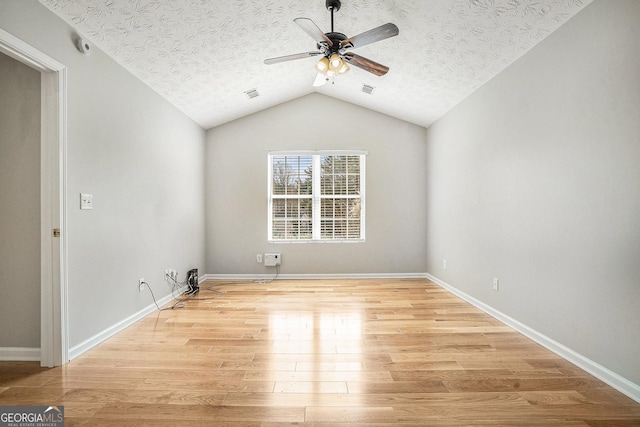 empty room featuring ceiling fan, a textured ceiling, lofted ceiling, baseboards, and light wood-style floors