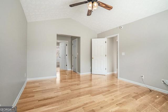 interior space with vaulted ceiling, ceiling fan, light wood-style flooring, and baseboards