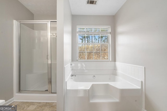 bathroom featuring a textured ceiling, visible vents, a stall shower, and a bath