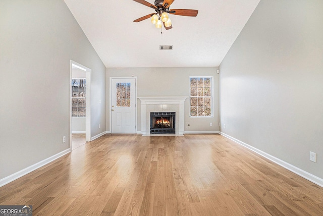 unfurnished living room featuring visible vents, baseboards, light wood-style flooring, ceiling fan, and a fireplace with flush hearth