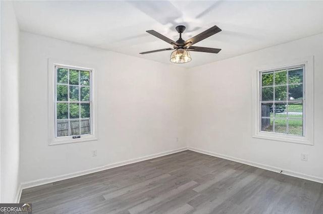 spare room featuring a ceiling fan, dark wood finished floors, and baseboards