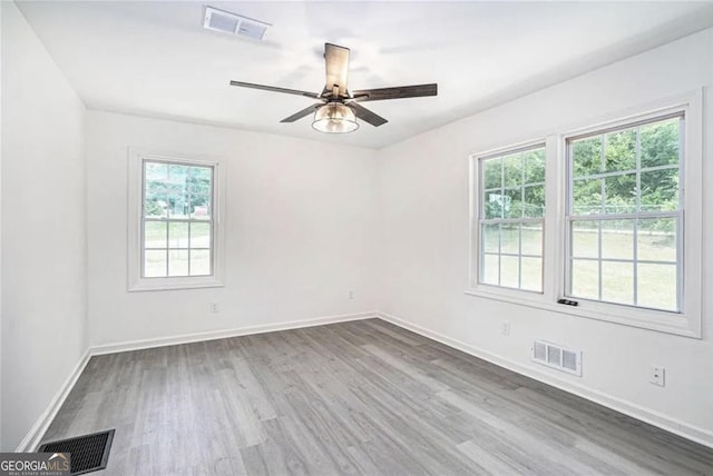 spare room with dark wood finished floors, visible vents, and baseboards