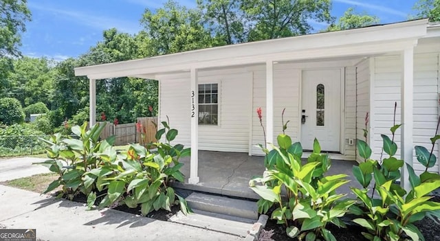 property entrance with covered porch and fence