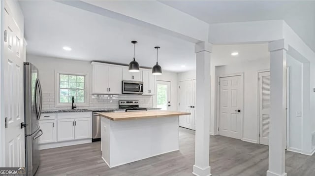 kitchen featuring wooden counters, appliances with stainless steel finishes, a sink, and white cabinets