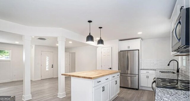 kitchen featuring light wood finished floors, visible vents, freestanding refrigerator, a sink, and butcher block countertops