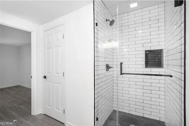 full bathroom with wood finished floors, a shower stall, and baseboards