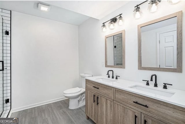 bathroom with wood finished floors, a sink, toilet, and a shower stall