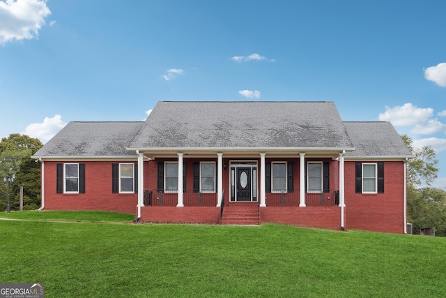 view of front of property with covered porch, a shingled roof, a front lawn, and brick siding