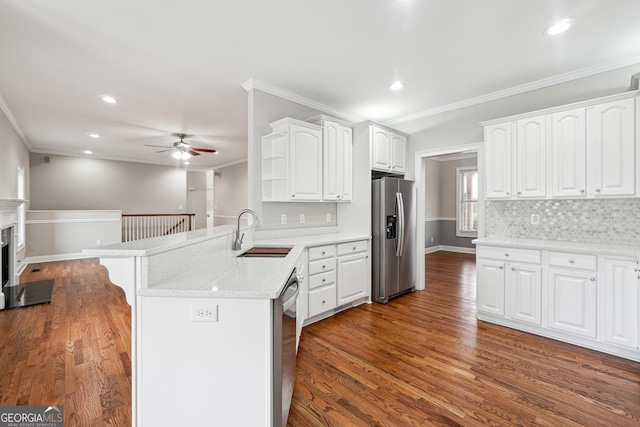 kitchen featuring a peninsula, white cabinets, stainless steel appliances, and a sink