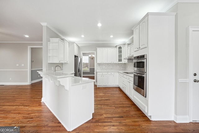 kitchen featuring a breakfast bar, appliances with stainless steel finishes, dark wood-type flooring, glass insert cabinets, and a peninsula