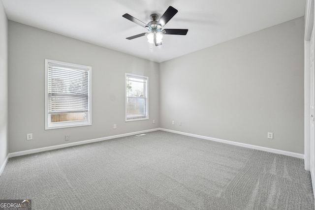 carpeted spare room with ceiling fan and baseboards