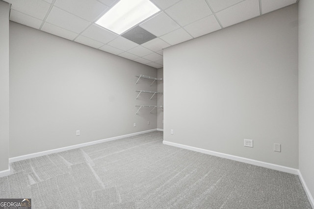 spare room with carpet, a drop ceiling, and baseboards