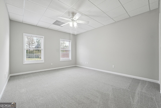 unfurnished room with carpet floors, baseboards, a drop ceiling, and a ceiling fan