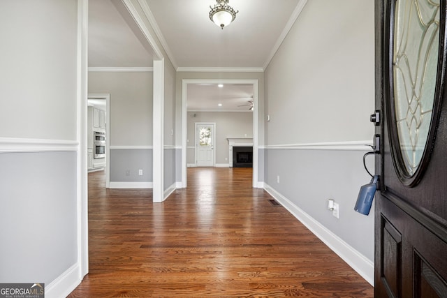 entrance foyer with a fireplace, crown molding, baseboards, and wood finished floors