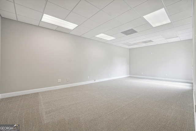 carpeted spare room with a paneled ceiling and baseboards