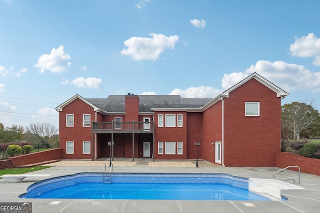 outdoor pool with a patio, a deck, and a diving board