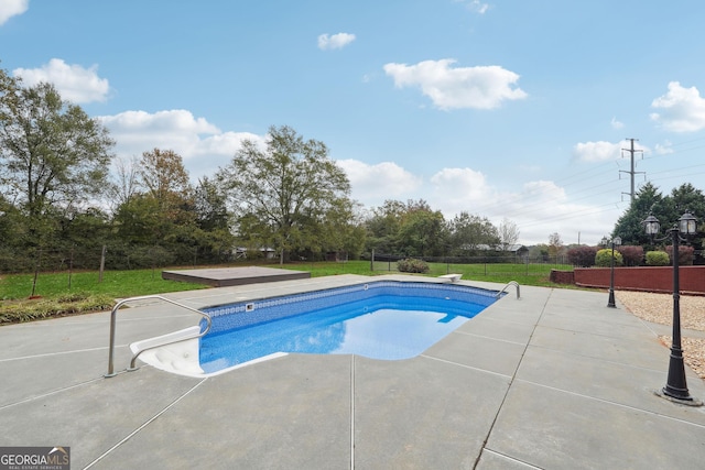 view of pool with a fenced in pool, a patio, a lawn, fence, and a diving board