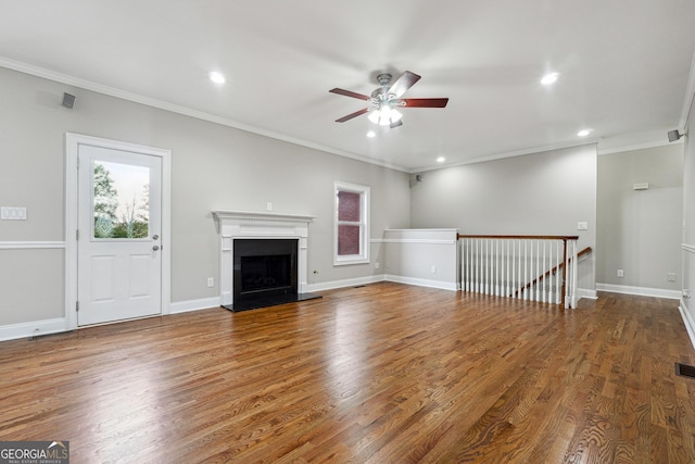 unfurnished living room with baseboards, a fireplace with raised hearth, a wealth of natural light, and wood finished floors