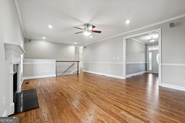 unfurnished living room featuring ceiling fan, ornamental molding, wood finished floors, and baseboards