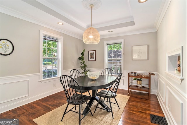dining area featuring visible vents, dark wood-style floors, a wainscoted wall, a tray ceiling, and crown molding