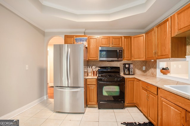 kitchen featuring appliances with stainless steel finishes, a tray ceiling, and light tile patterned floors