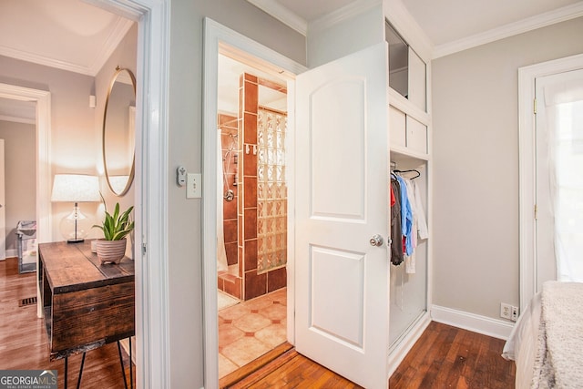 full bath featuring wood-type flooring, ornamental molding, a tile shower, and baseboards
