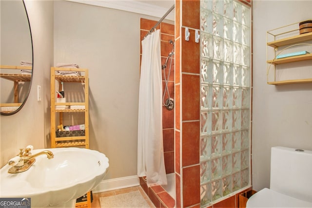 full bathroom with baseboards, toilet, tile patterned floors, a tile shower, and a sink