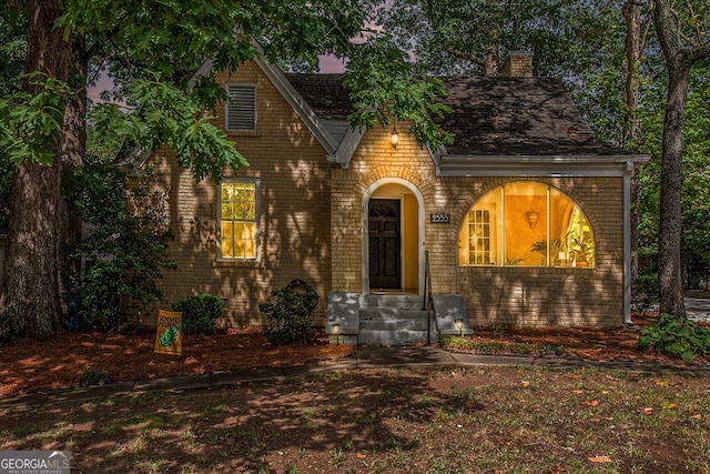 english style home with brick siding and a chimney