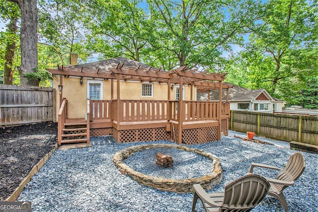 rear view of property featuring a fire pit, a deck, and stucco siding