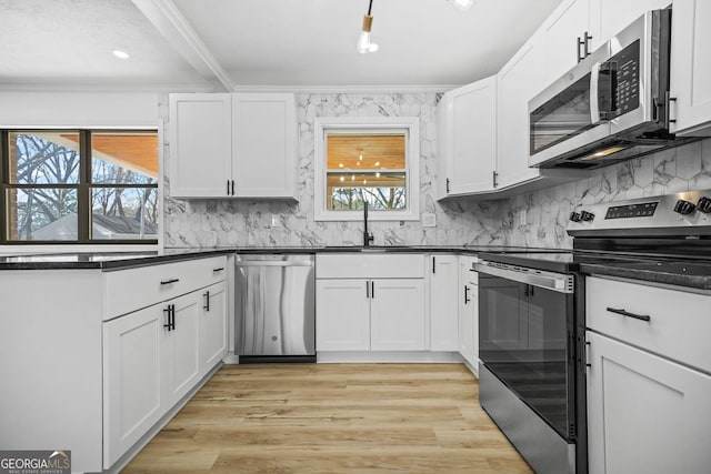 kitchen with dark countertops, light wood-style floors, ornamental molding, and stainless steel appliances